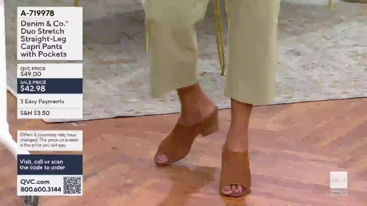 A woman's feet, clad in tan mules, move across a wooden floor. She's wearing light-colored capri pants, the kind you'd see on QVC.