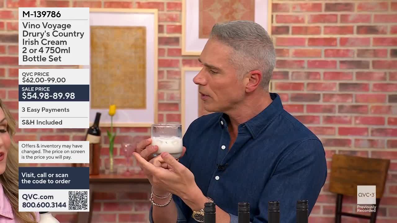 A man holds up a glass of creamy white liquid, gesturing with his other hand. He's on QVC, talking about Vino Voyage Irish Cream.