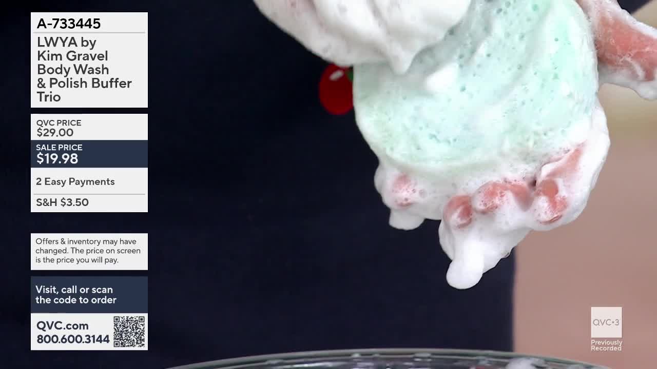 Hands are squeezing a pale green, foamy buffer, creating a cascade of suds. The buffer, part of a body wash trio from Kim Gravel, is slick with soap.