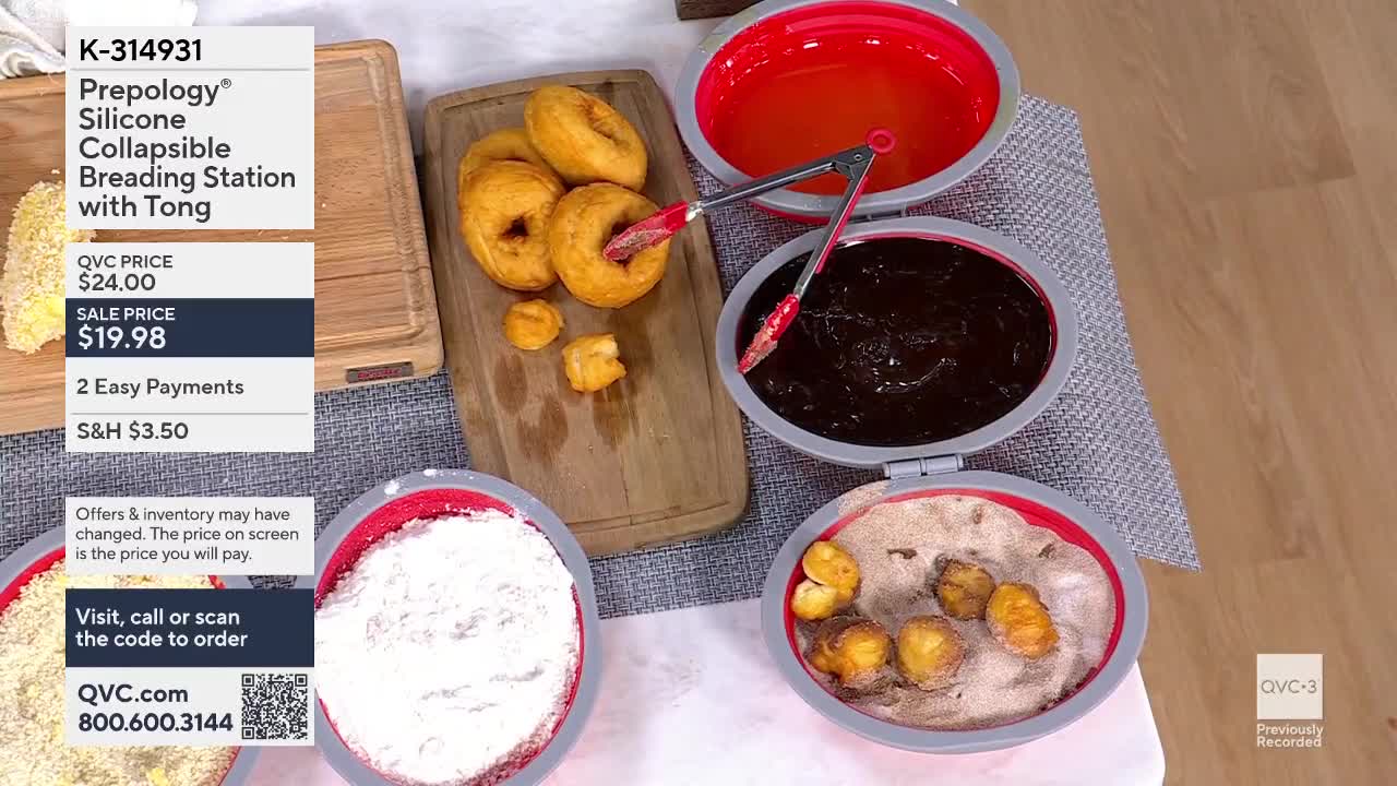 A pair of red tongs lifts a golden-brown donut from a wooden board. Another set of tongs dips a donut into a dark, glossy glaze.