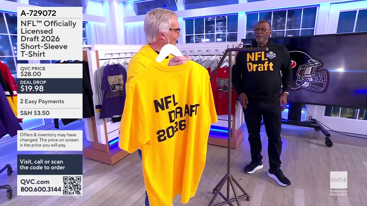 A man holds up a bright yellow t-shirt with "NFL DRAFT 2026" printed on the back. Another man stands nearby wearing a black long-sleeved shirt with the same NFL Draft logo.