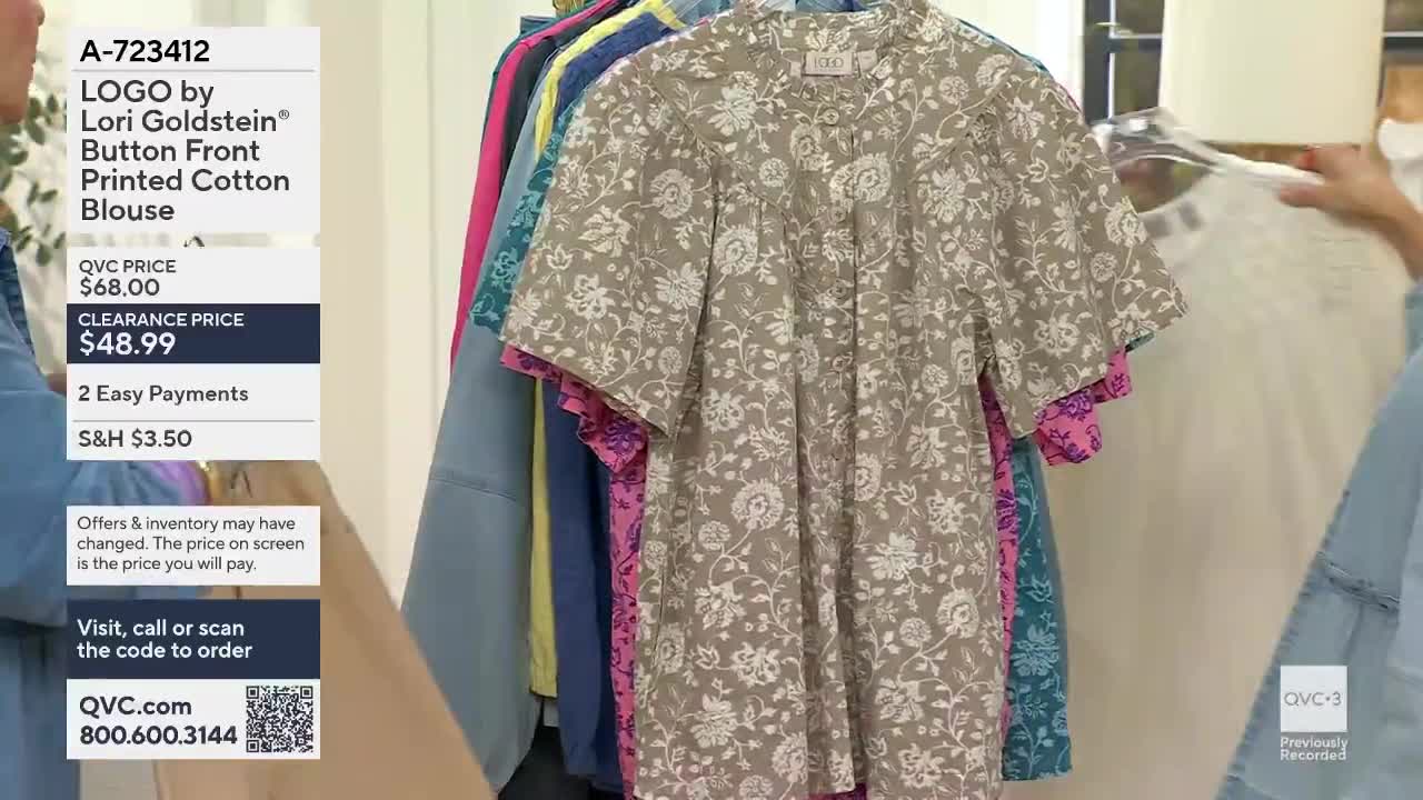 A hand reaches out to adjust a printed blouse hanging on a rack. The QVC logo is visible in the corner.
