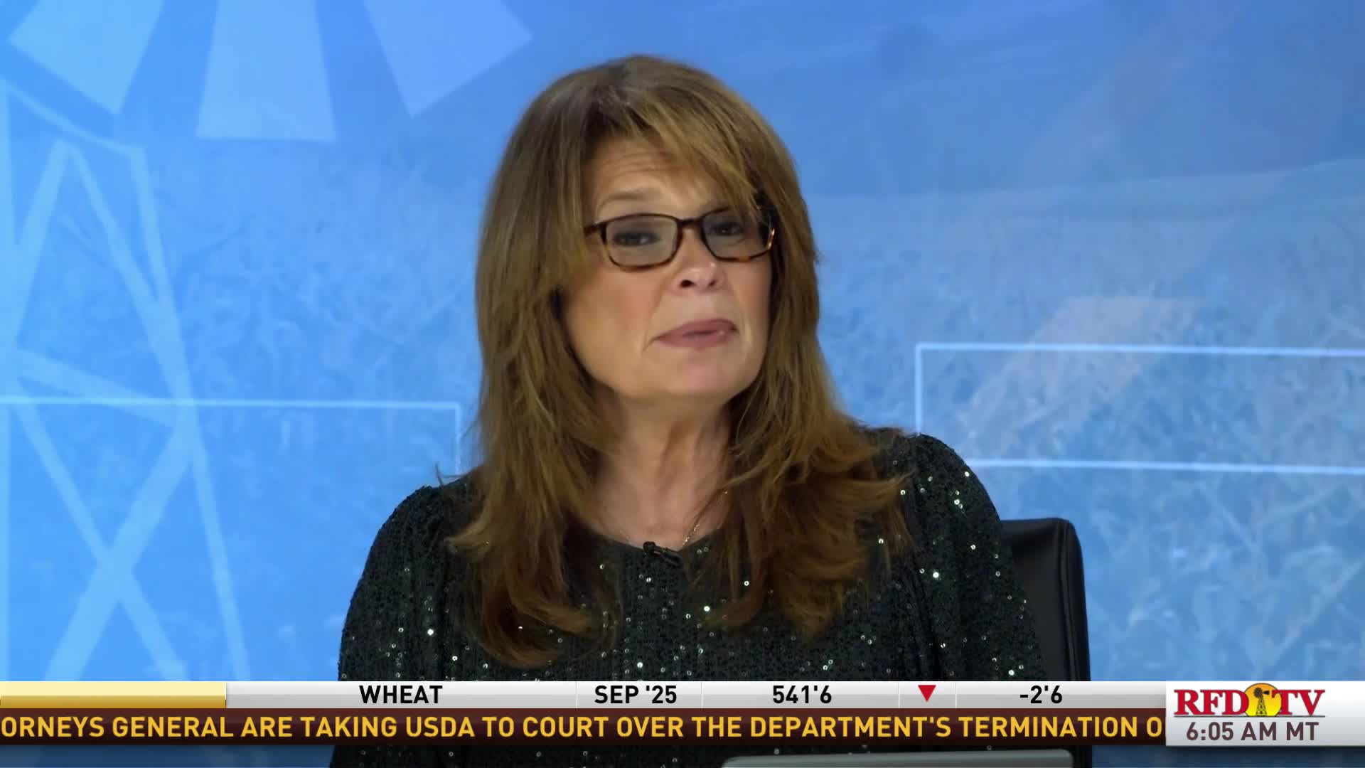 The woman in glasses is speaking, framed against a blue backdrop. A ticker at the bottom of the screen scrolls information, and the RFD-TV logo is visible.
