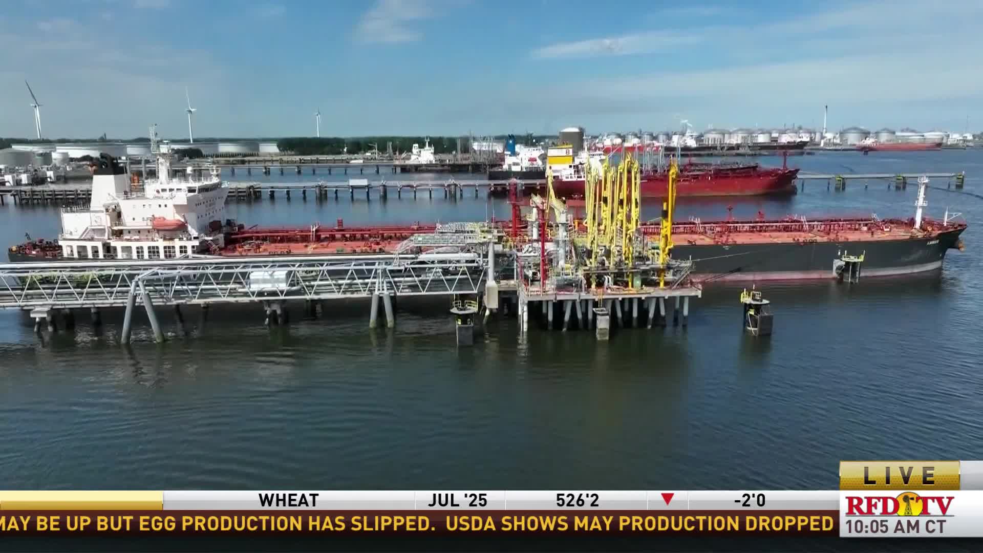 A large tanker is docked at a pier, connected by yellow pipes and a walkway. The RFD-TV broadcast shows a sunny day with other ships and industrial structures in the background.
