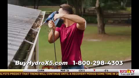 A man in a red shirt is using a blue power tool to clear out a gutter. Debris is being blasted away, and the scene appears to be a commercial on RFD-TV.
