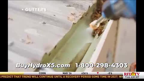 A high-pressure nozzle blasts water into a gutter, dislodging debris. The scene is part of a commercial on RFD-TV, advertising a product called BuyHydroX5.
