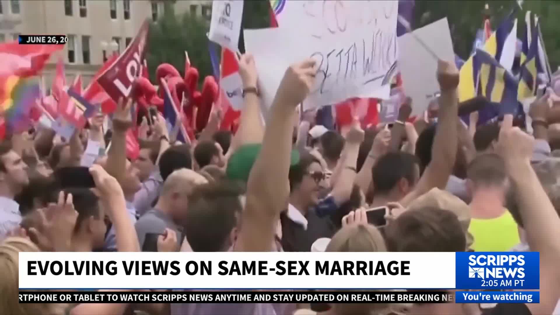 A crowd is gathered, their arms raised with signs and flags. The Scripps News graphic at the bottom indicates a story about evolving views on same-sex marriage.
