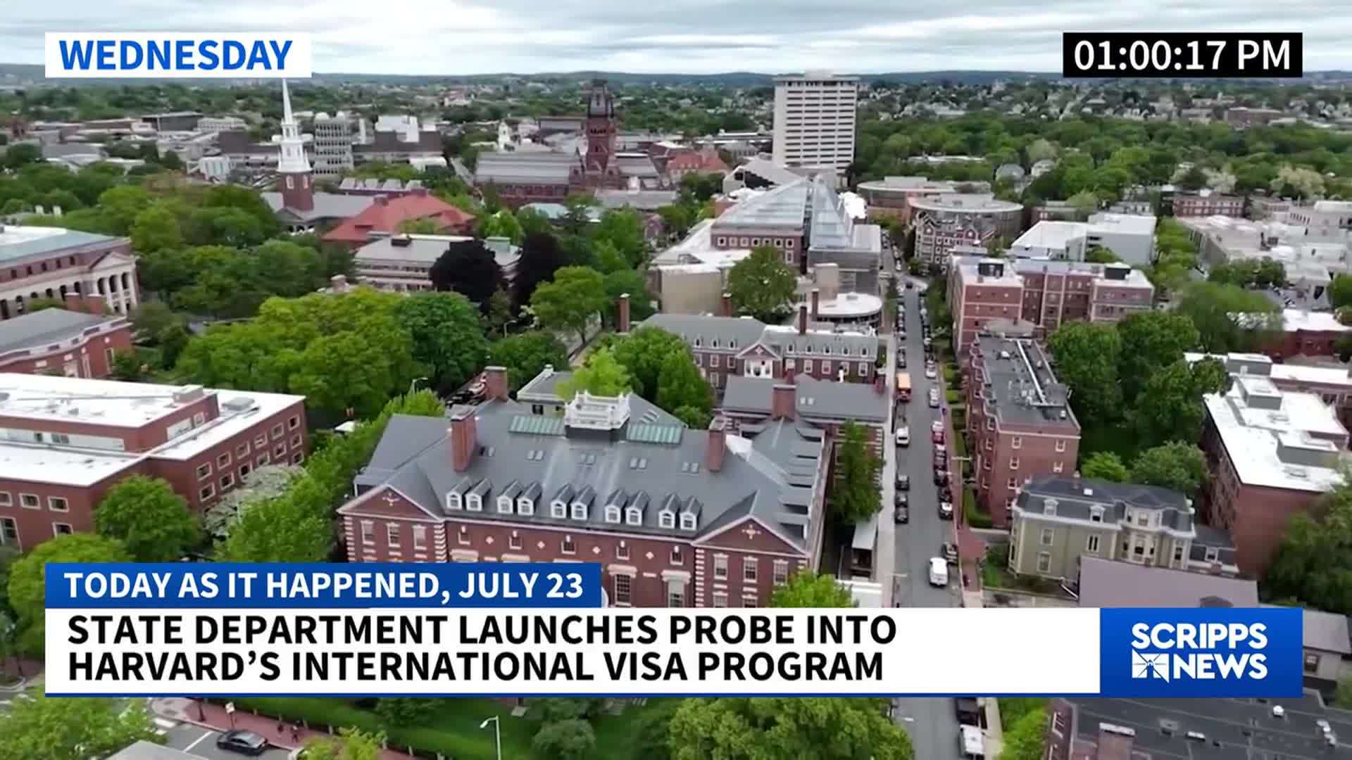 From this aerial view, I see red brick buildings and green trees lining a street. A Scripps News graphic at the bottom of the screen reports a State Department probe into Harvard's international visa program.
