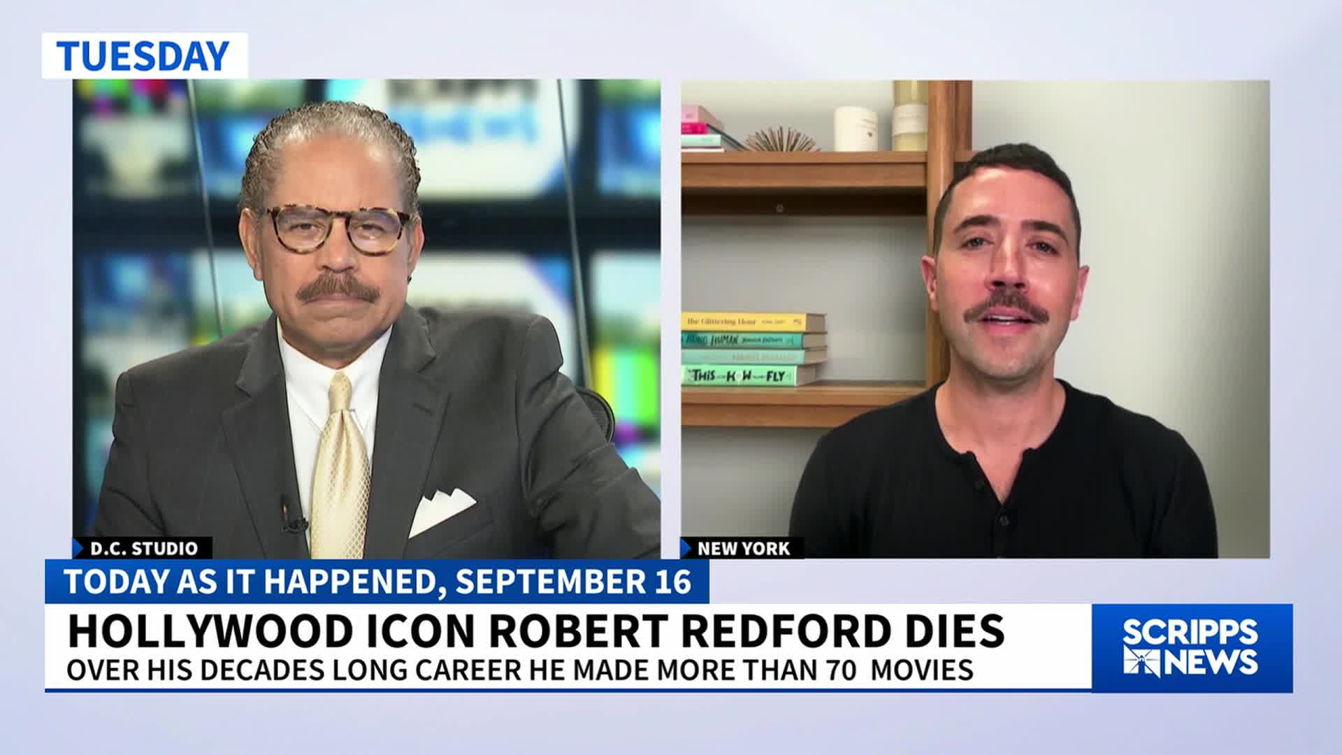 A news anchor in a suit sits across from a man in a black shirt, both appearing on a Scripps News broadcast. The chyron announces the death of Robert Redford, a Hollywood icon.
