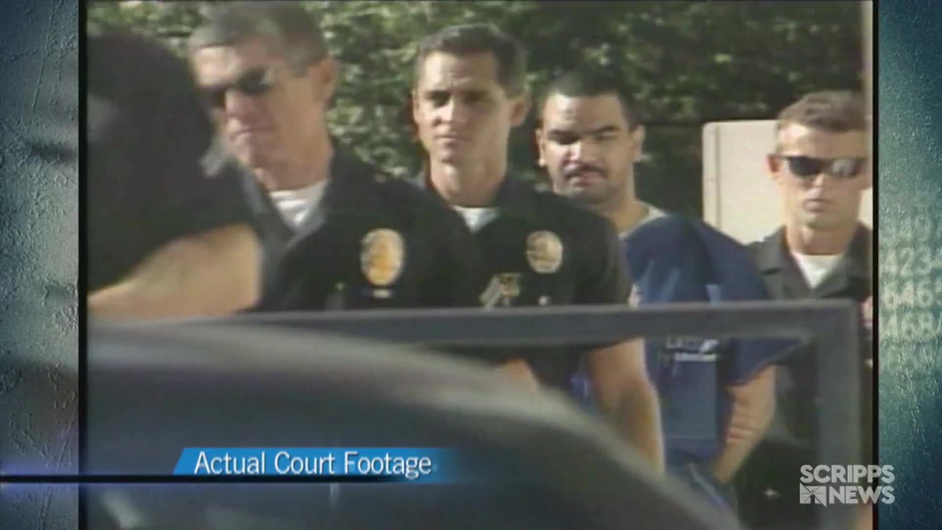 A man in a blue shirt is being escorted by police officers, the group moving slowly forward. The "Actual Court Footage" label and Scripps News logo indicate this is a news report from the United States.
