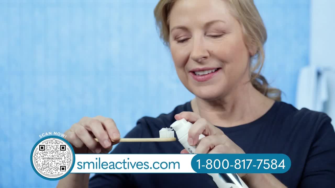 A woman is squeezing toothpaste onto a toothbrush, her face lit with a smile. The ad for "smileactives.com" and a phone number are displayed in the lower corner.
