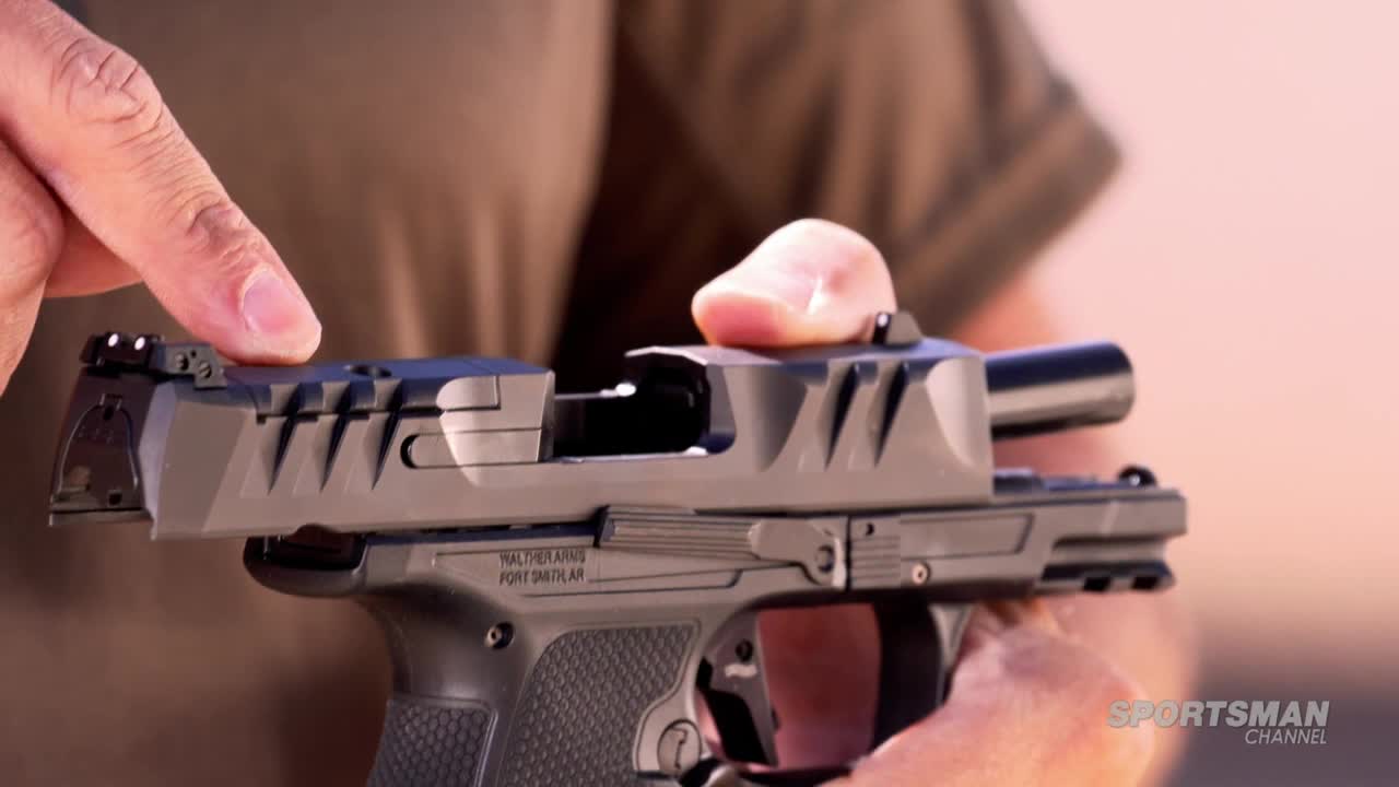 A hand is pulling back the top of a black handgun, exposing the inner workings. The Sportsman Channel logo is visible in the corner.
