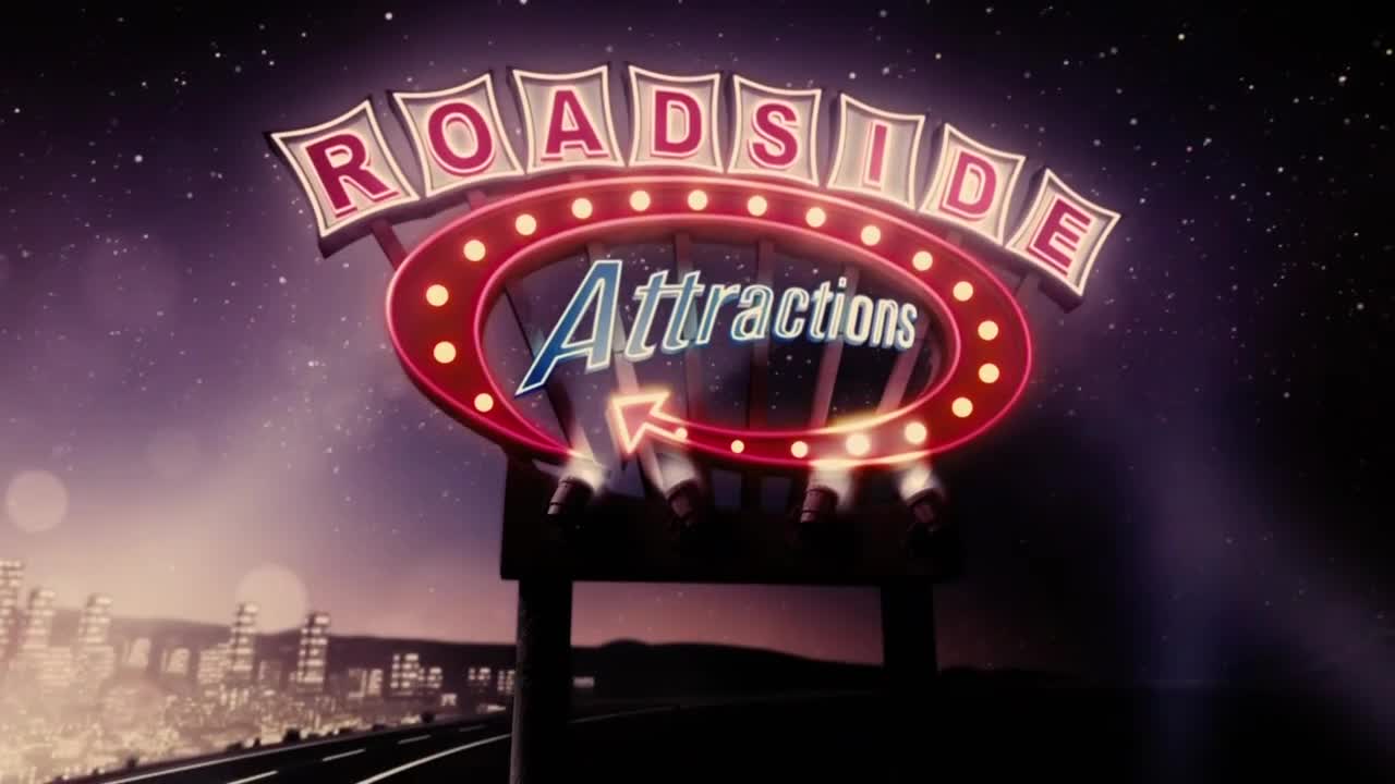 A neon sign that reads "Roadside Attractions" glows against a starry sky. Below, the lights of a city shimmer on the horizon.
