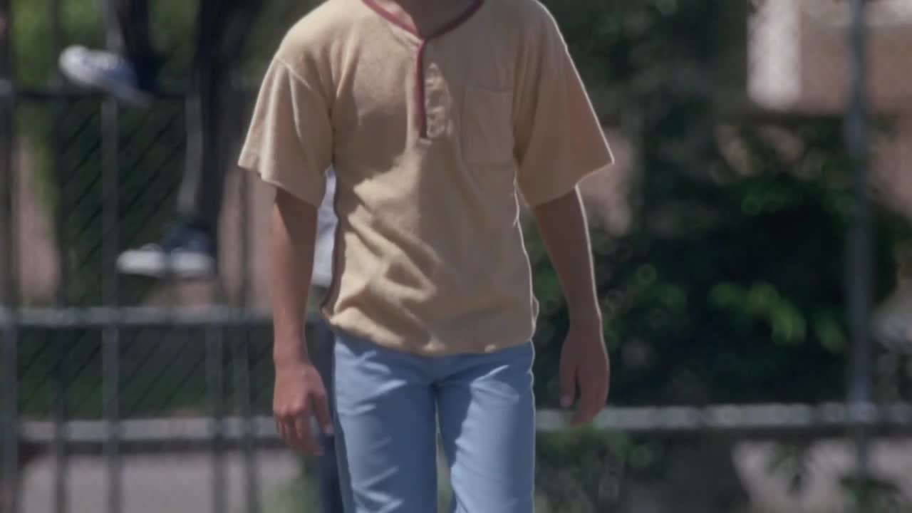 A young boy, clad in a light-colored shirt and jeans, walks toward me. His body is centered, and he appears to be in motion.
