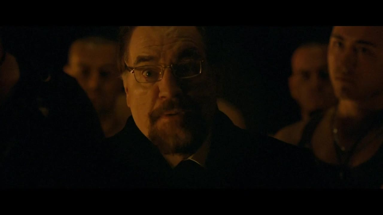 A man with glasses and a beard is speaking, his eyes wide and focused. He's surrounded by others, the scene lit dimly, likely in the United States, a Starz Encore Classic production.
