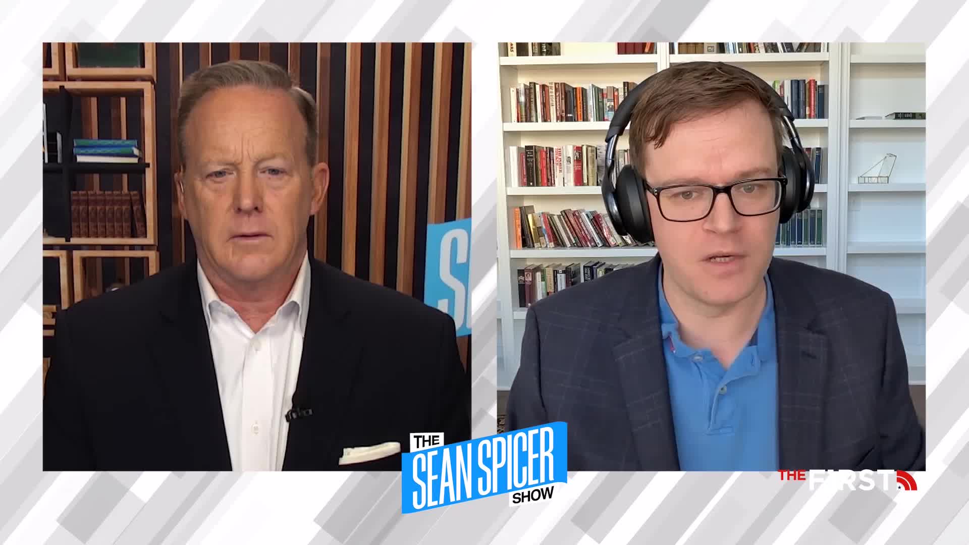 Sean Spicer, in a dark suit, sits facing the camera, while another man wearing headphones and glasses speaks from a home office setting. The First TV logo is visible in the corner, and the show's title card, "The Sean Spicer Show," is below Spicer.
