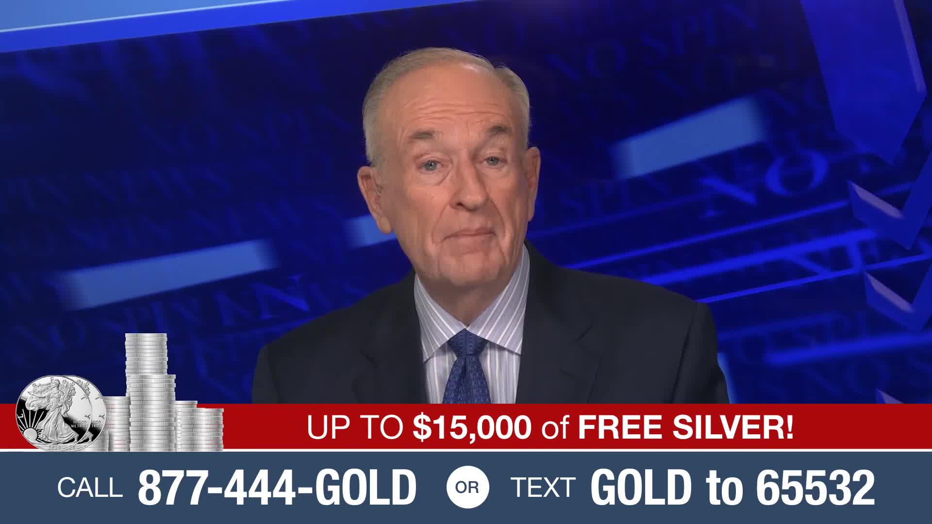 A man in a suit is speaking on a television set, against a blue backdrop. Below him, a banner advertises free silver and provides a phone number and a text code.
