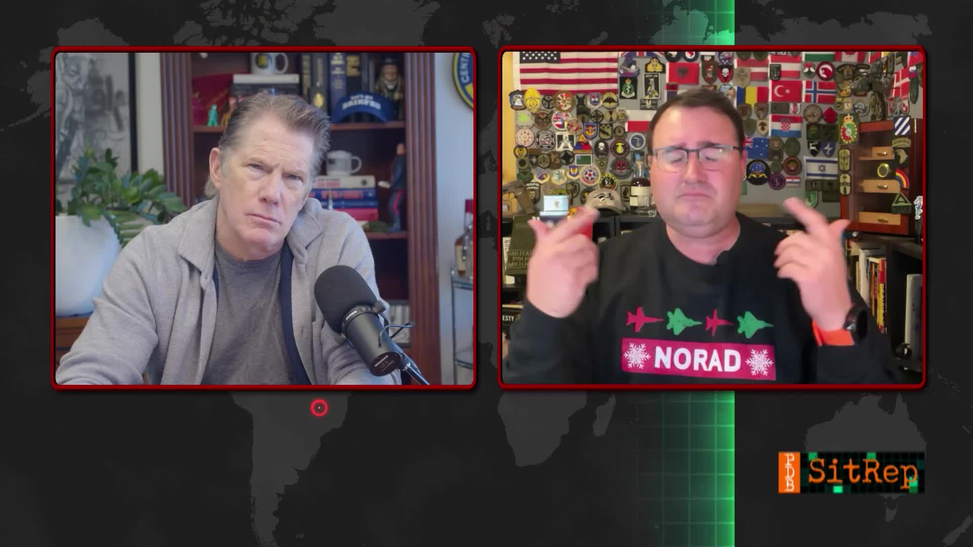 Two men are on a split screen, likely a broadcast from The First TV in the United States. The man on the right gestures with both hands while wearing a sweater with the word "NORAD" on it.
Two men are on a split screen, likely a broadcast from The First TV in the United States. The man on the right gestures with both hands while wearing a sweater with the word "NORAD" on it.