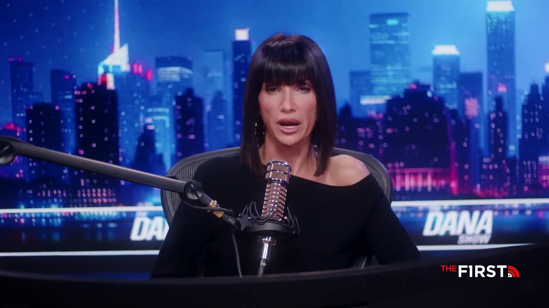 The host of "The Dana Show" on The First TV, in the United States, is speaking directly into a microphone. Behind her, a cityscape backdrop glows with lights.
The host of "The Dana Show" on The First TV, in the United States, is speaking directly into a microphone. Behind her, a cityscape backdrop glows with lights.