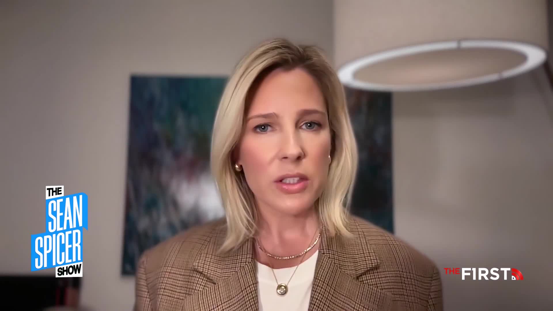 A woman with blonde hair, wearing a plaid blazer, speaks directly to the camera. A logo for "The Sean Spicer Show" appears on the left side of the screen.