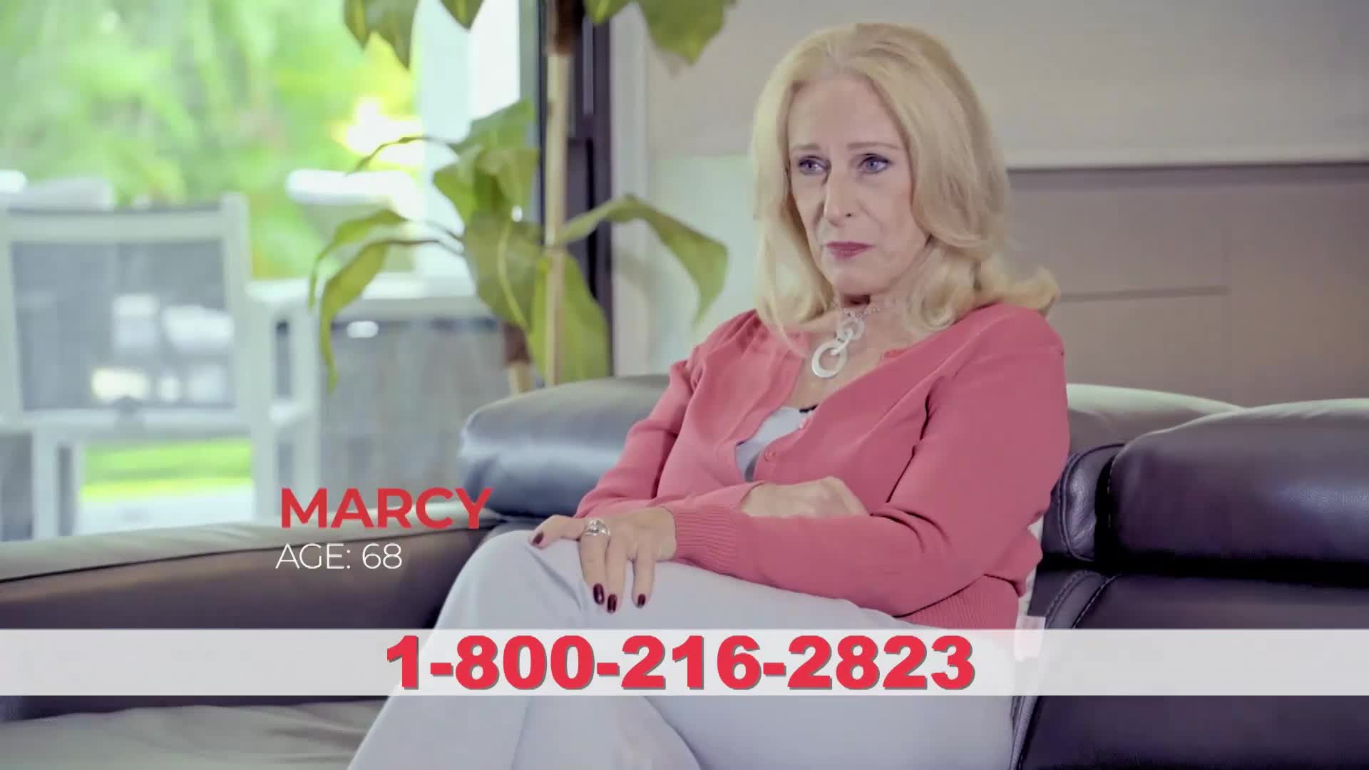 A woman named Marcy, age 68, sits on a couch. A phone number flashes across the bottom of the screen.