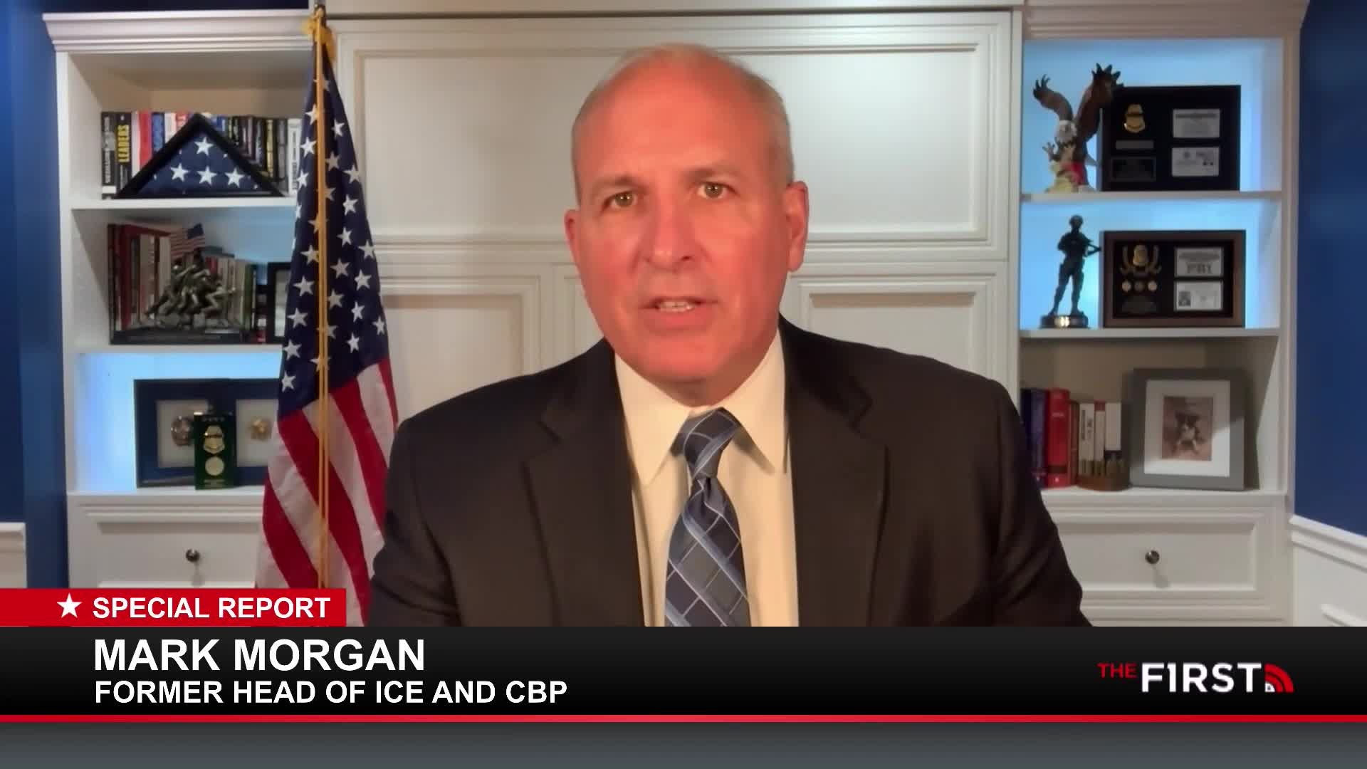 A man in a suit speaks directly to the camera, an American flag behind him. The First TV logo appears at the bottom right of the screen.