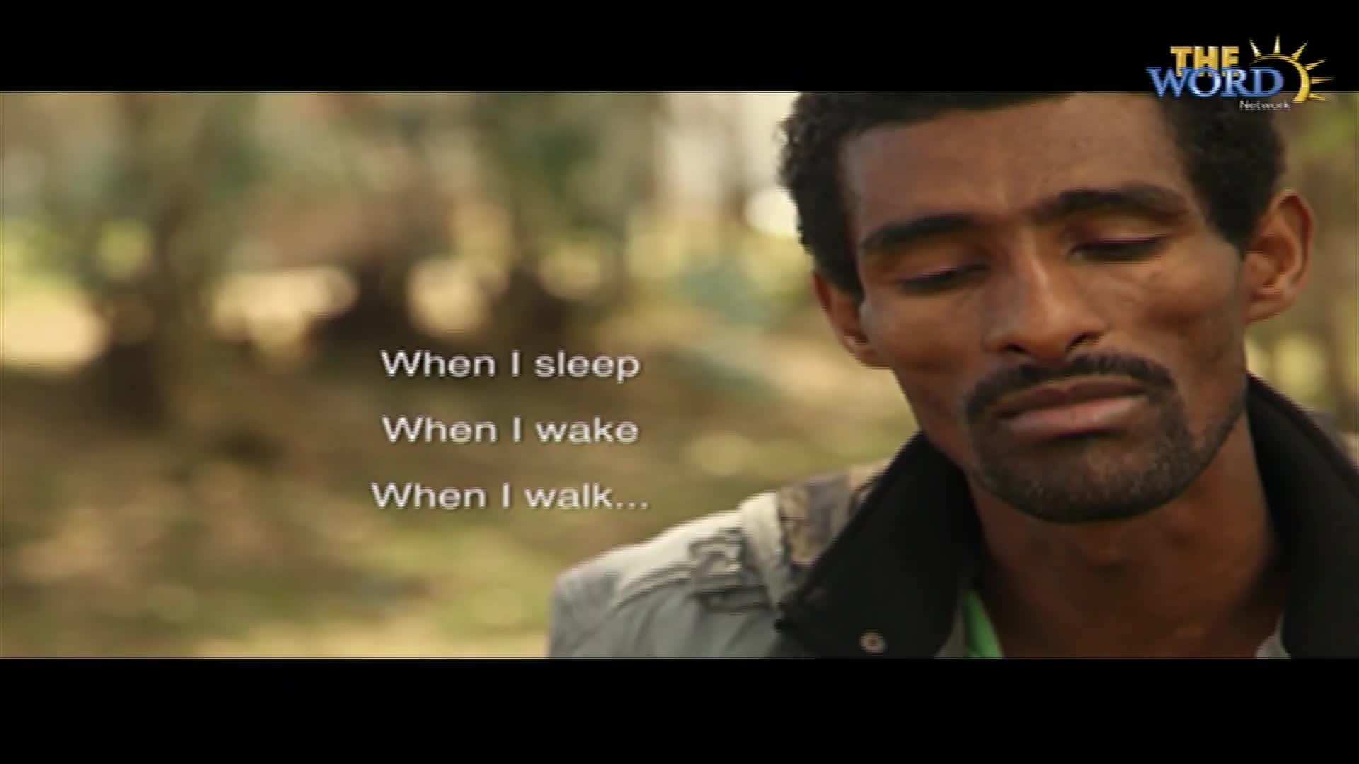 A man with a thin mustache and beard looks down, eyes closed, as if in prayer. The Word Network logo sits in the top right corner, and text appears on the left.
