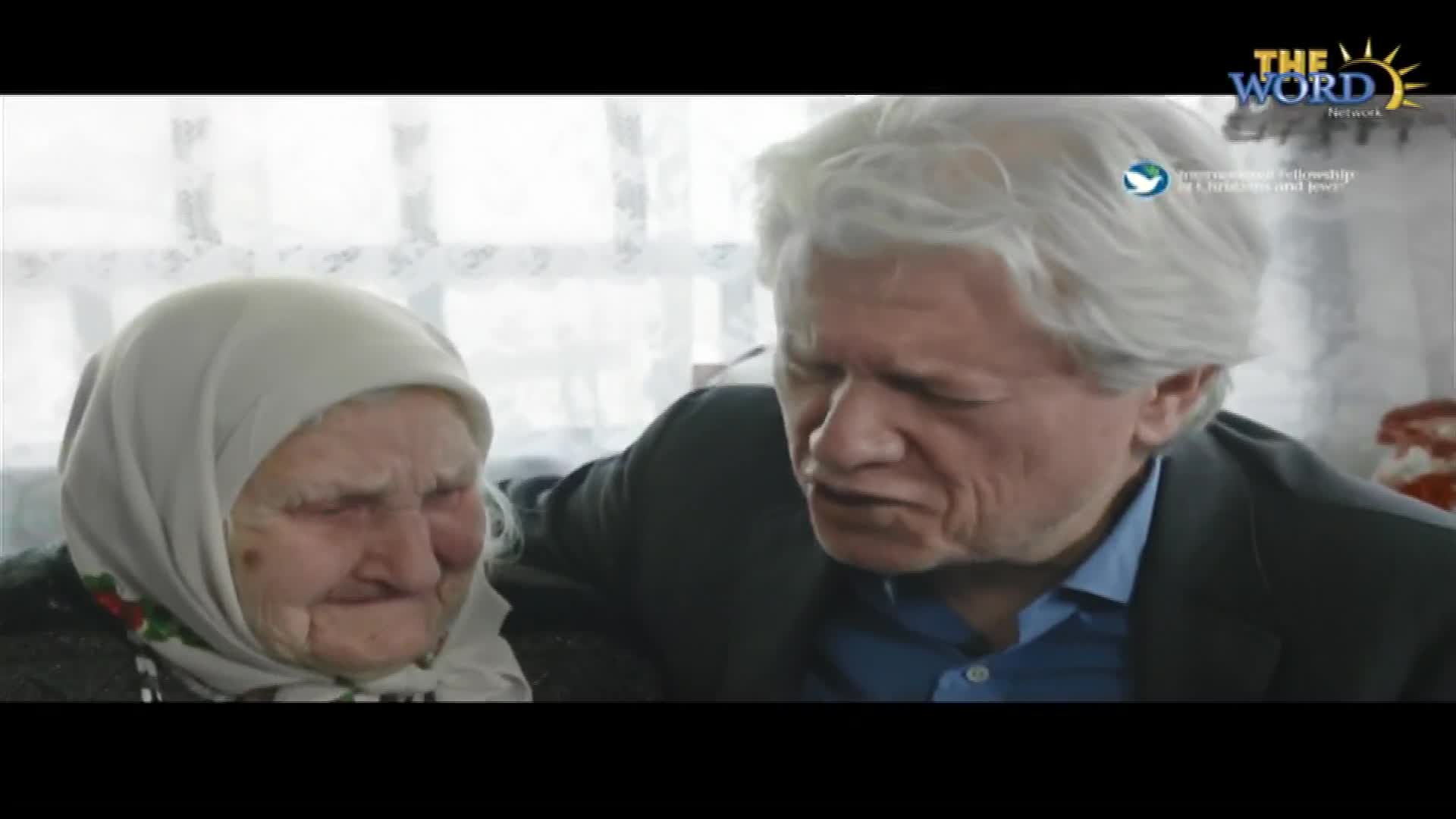 A man with silver hair leans in, speaking intently to an elderly woman wearing a headscarf. The Word Network logo is visible in the corner.
