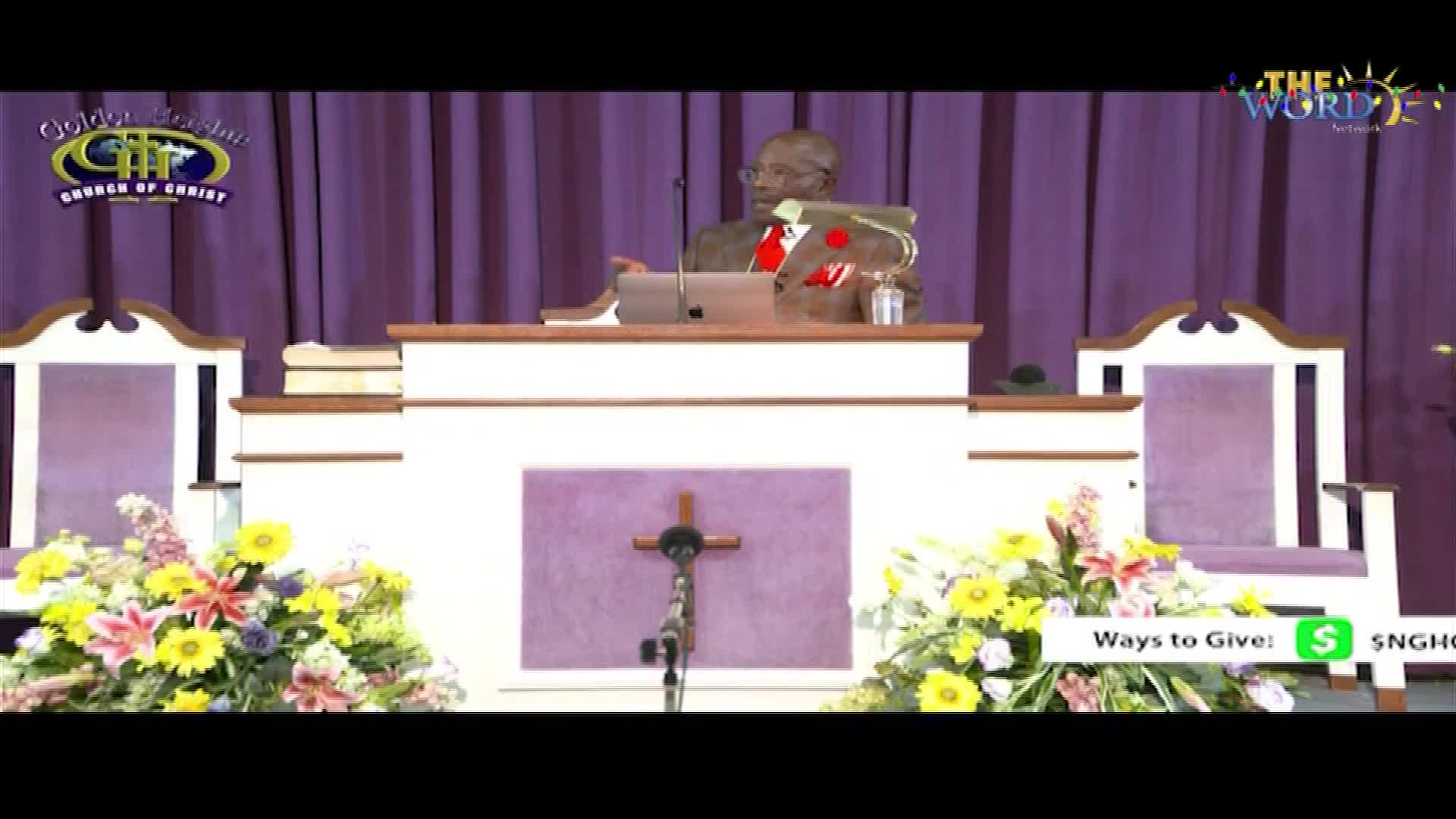 A man in a suit stands behind a pulpit, speaking into a microphone. The broadcast is on The Word Network, with a "Ways to Give" graphic displayed at the bottom.
