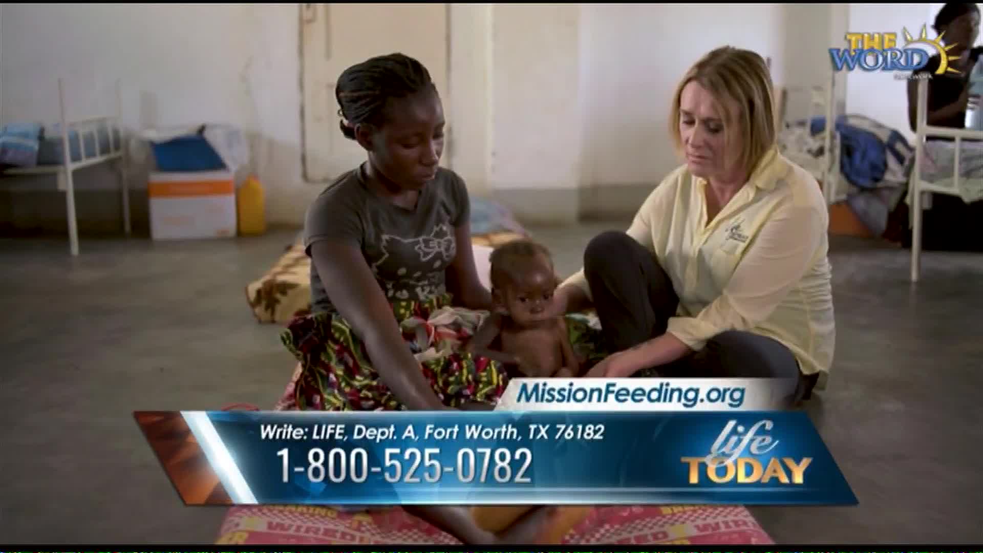 A woman in a patterned skirt cradles a small child while another woman, wearing a yellow shirt, kneels beside them. A graphic overlay displays "MissionFeeding.org" and a toll-free number.