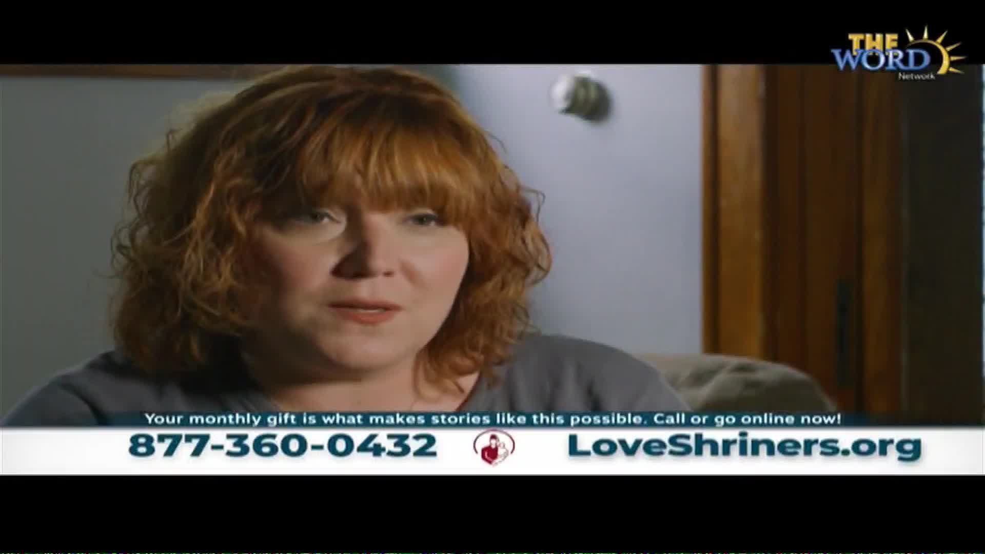 A woman with auburn hair speaks directly to the camera. A graphic at the bottom of the screen displays a phone number and website for LoveShriners.org, a ministry of The Word Network.