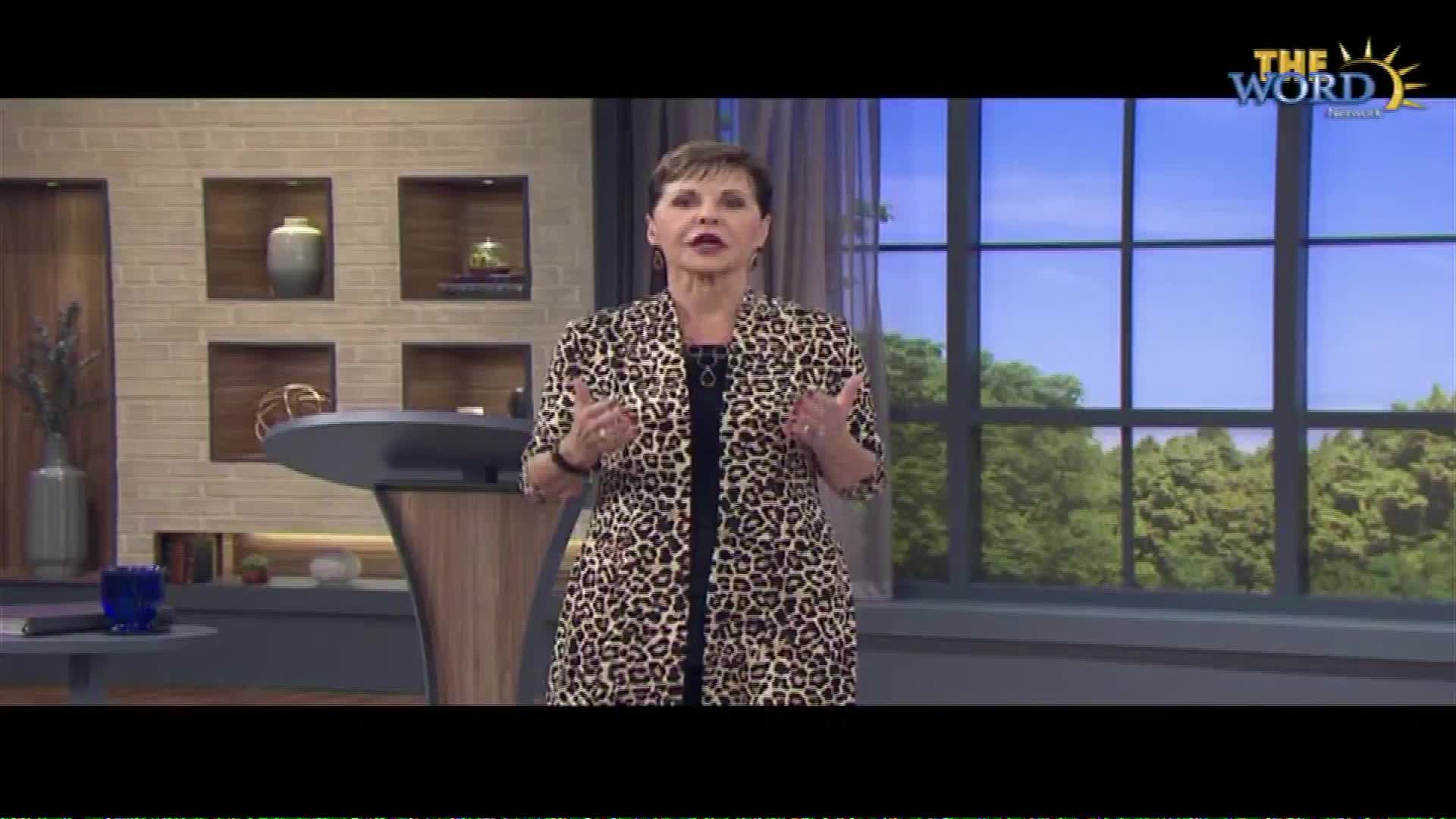 A woman in a leopard-print jacket stands before a large window, speaking with her hands. A logo for The Word Network appears in the upper right corner.
