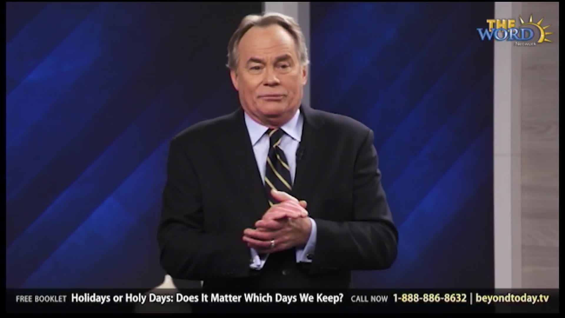 A man in a dark suit and striped tie stands with his hands clasped. The Word Network logo appears in the upper right corner of the screen.