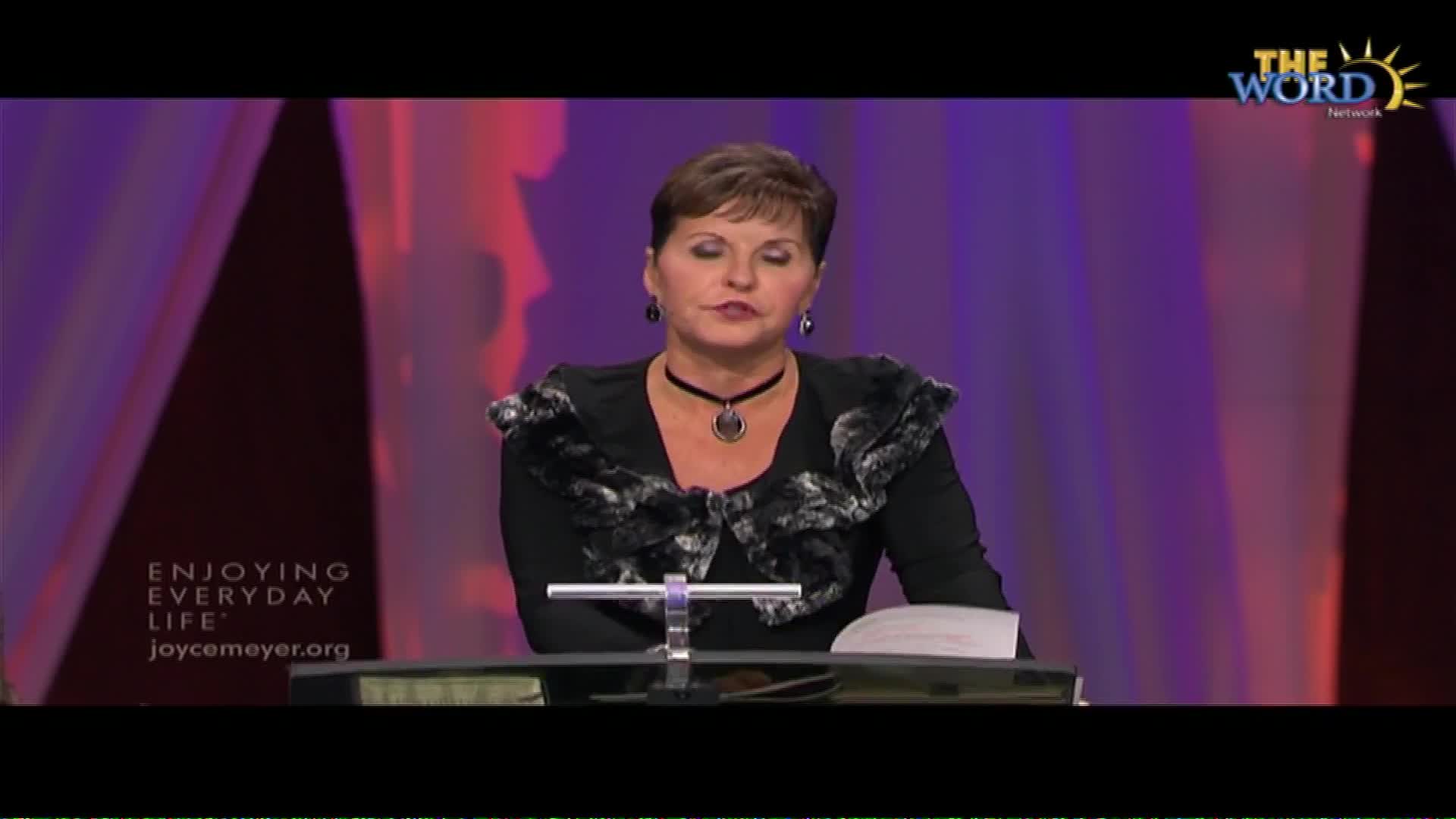 Joyce Meyer speaks from behind a podium, her gaze directed forward.  The Word Network logo appears in the upper right corner.