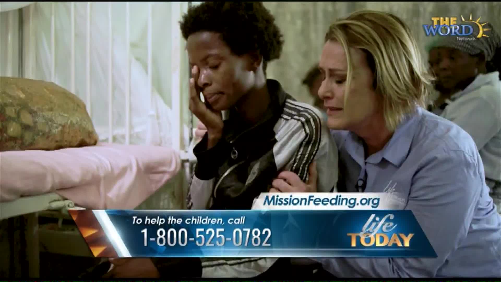 A woman comforts a crying young person in what looks like a hospital bed. A graphic overlay from The Word Network, a US-based broadcaster, displays a phone number for MissionFeeding.org.