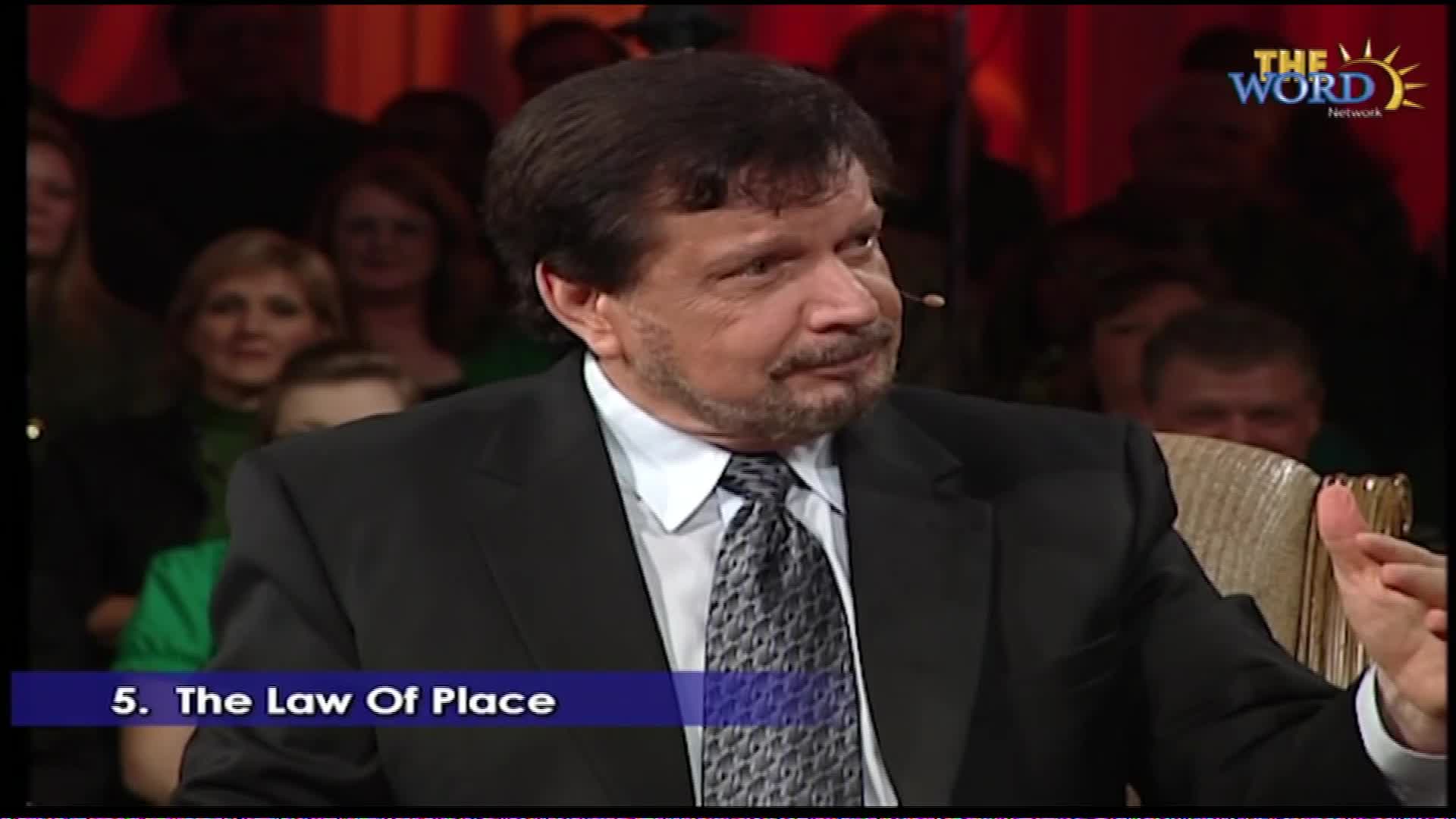 A man in a suit and tie speaks on a stage, with a logo for "The Word Network" visible behind him. The text "5. The Law Of Place" appears in a blue banner at the bottom of the screen.