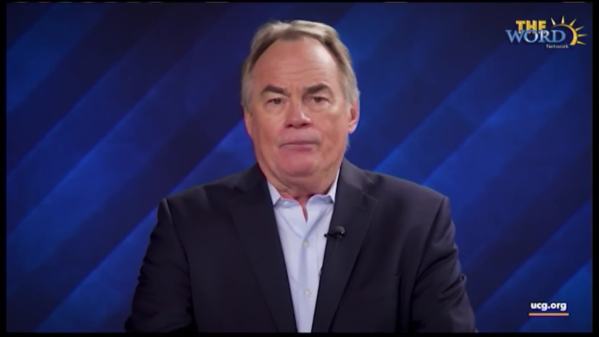 A man in a suit stands before a blue, striped background. The Word Network logo appears in the upper right corner.