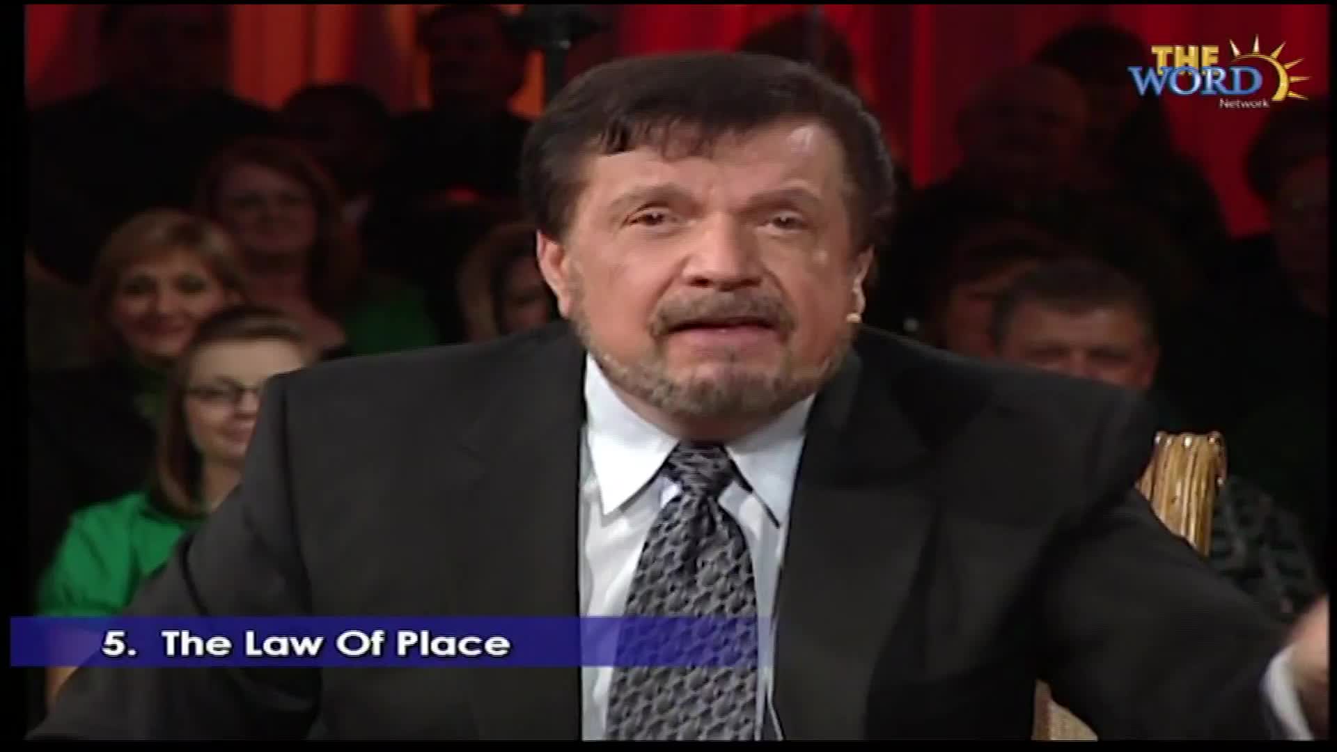 A man in a suit speaks directly to the camera, his audience visible behind him. The Word Network logo appears in the upper right corner.