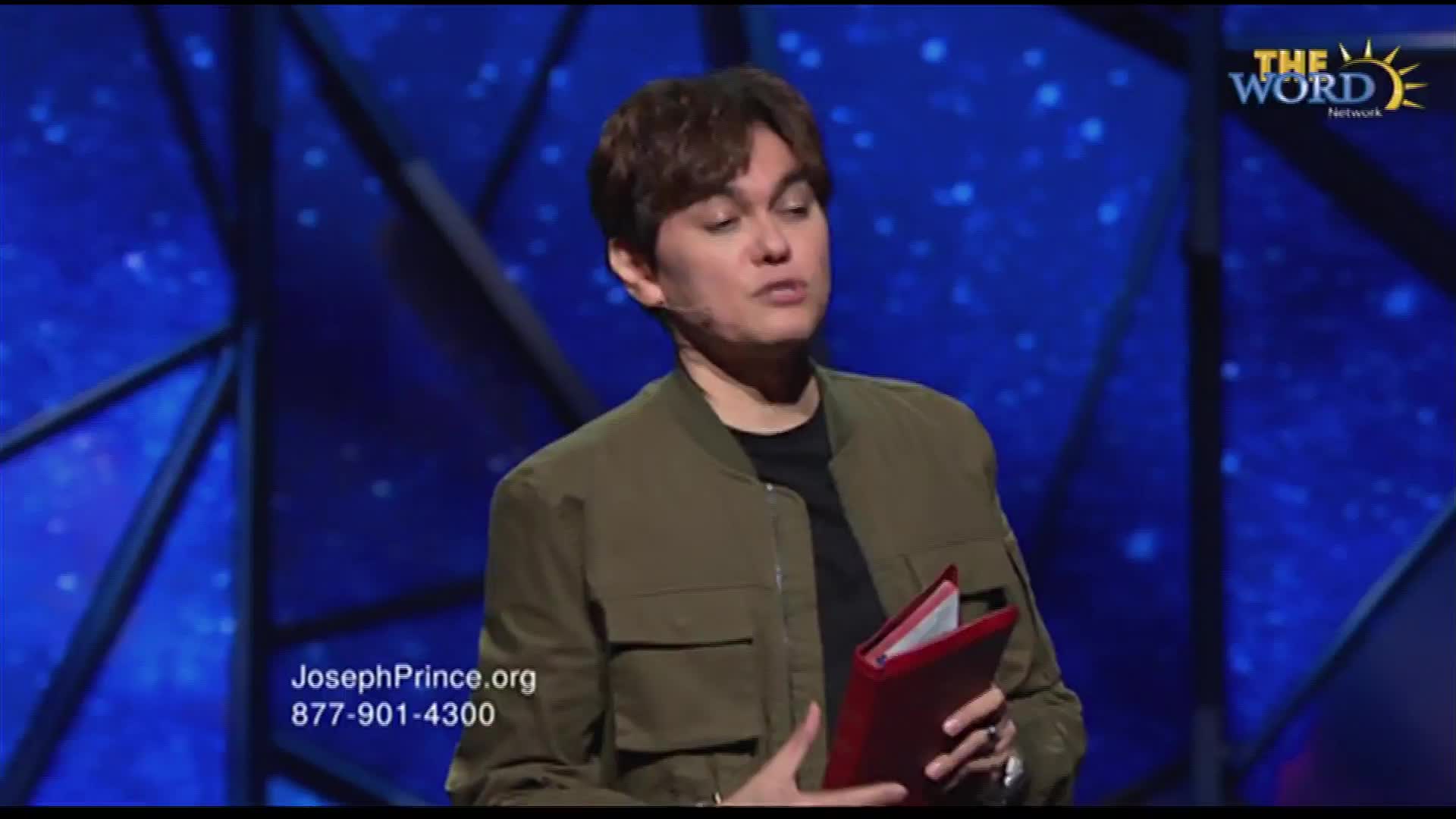 A speaker stands on a stage, holding a red book. The Word Network logo appears in the upper right corner.