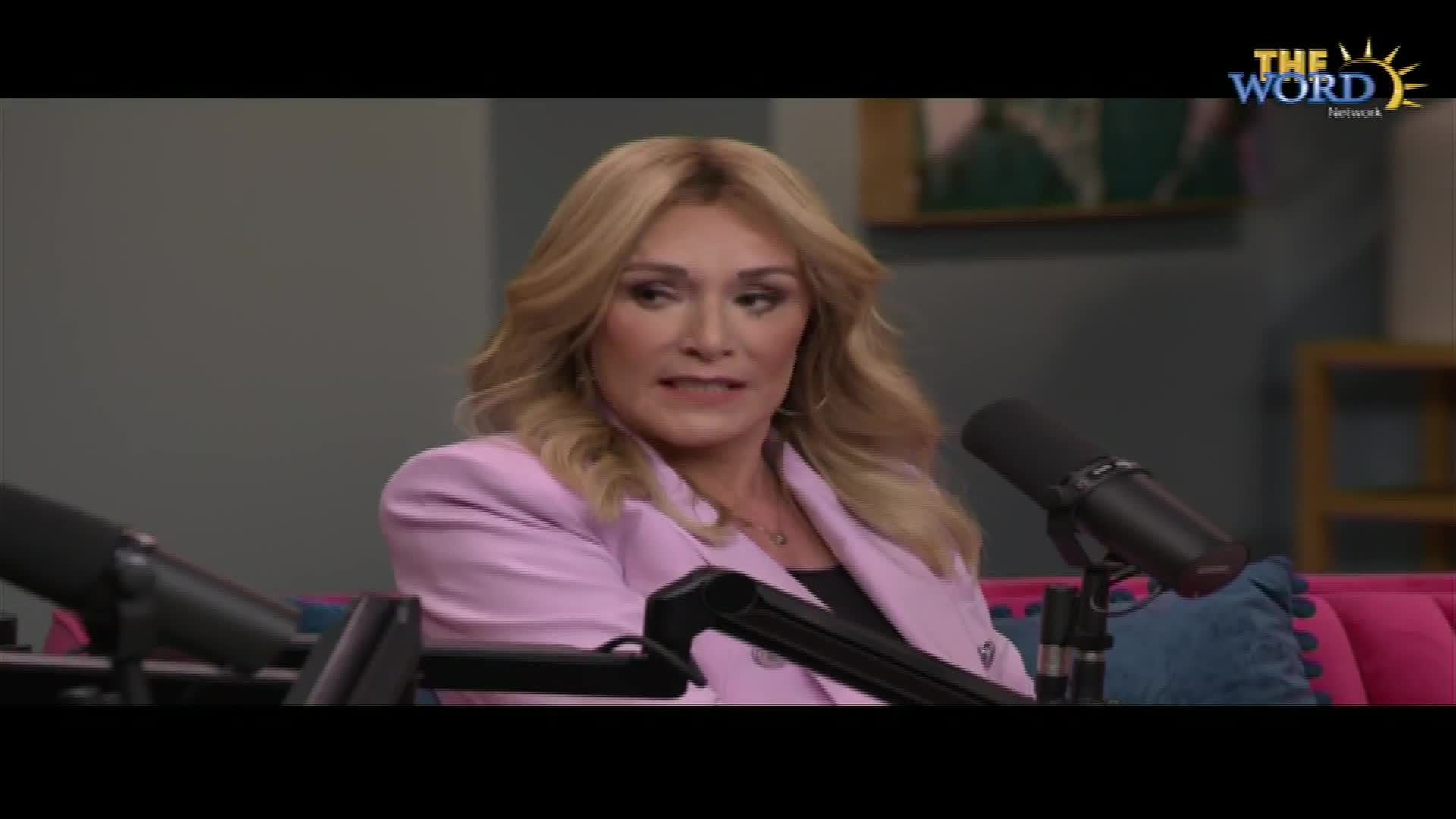 A woman with blonde hair, wearing a pink blazer, speaks into a microphone. The Word Network logo is visible in the upper right corner.