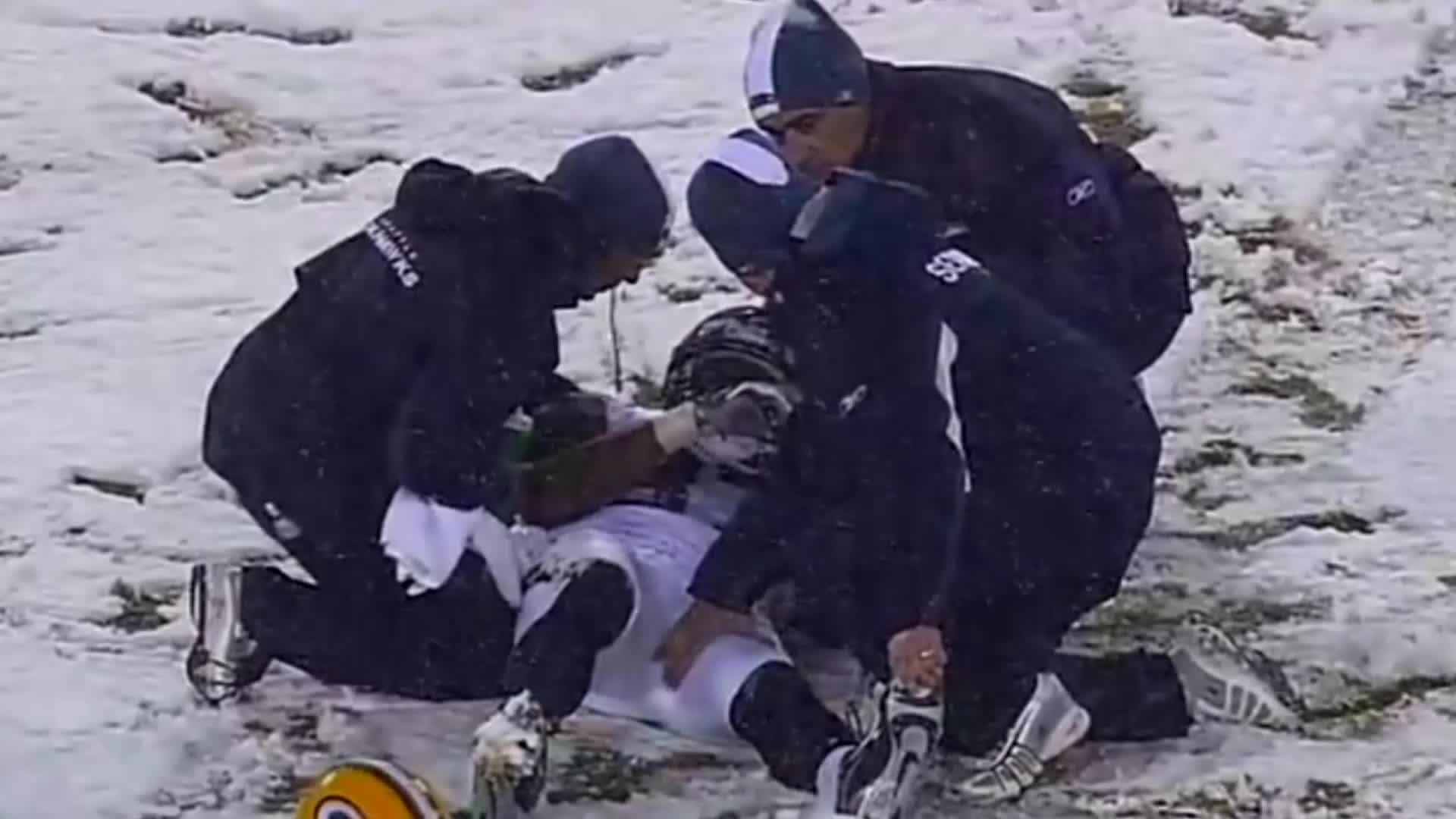 Medics huddle around a player on the snowy field, their black jackets contrasting with the white ground. One of them is holding a towel, while the others are focused on the injured man.
Medics huddle around a player on the snowy field, their black jackets contrasting with the white ground. One of them is holding a towel, while the others are focused on the injured man.