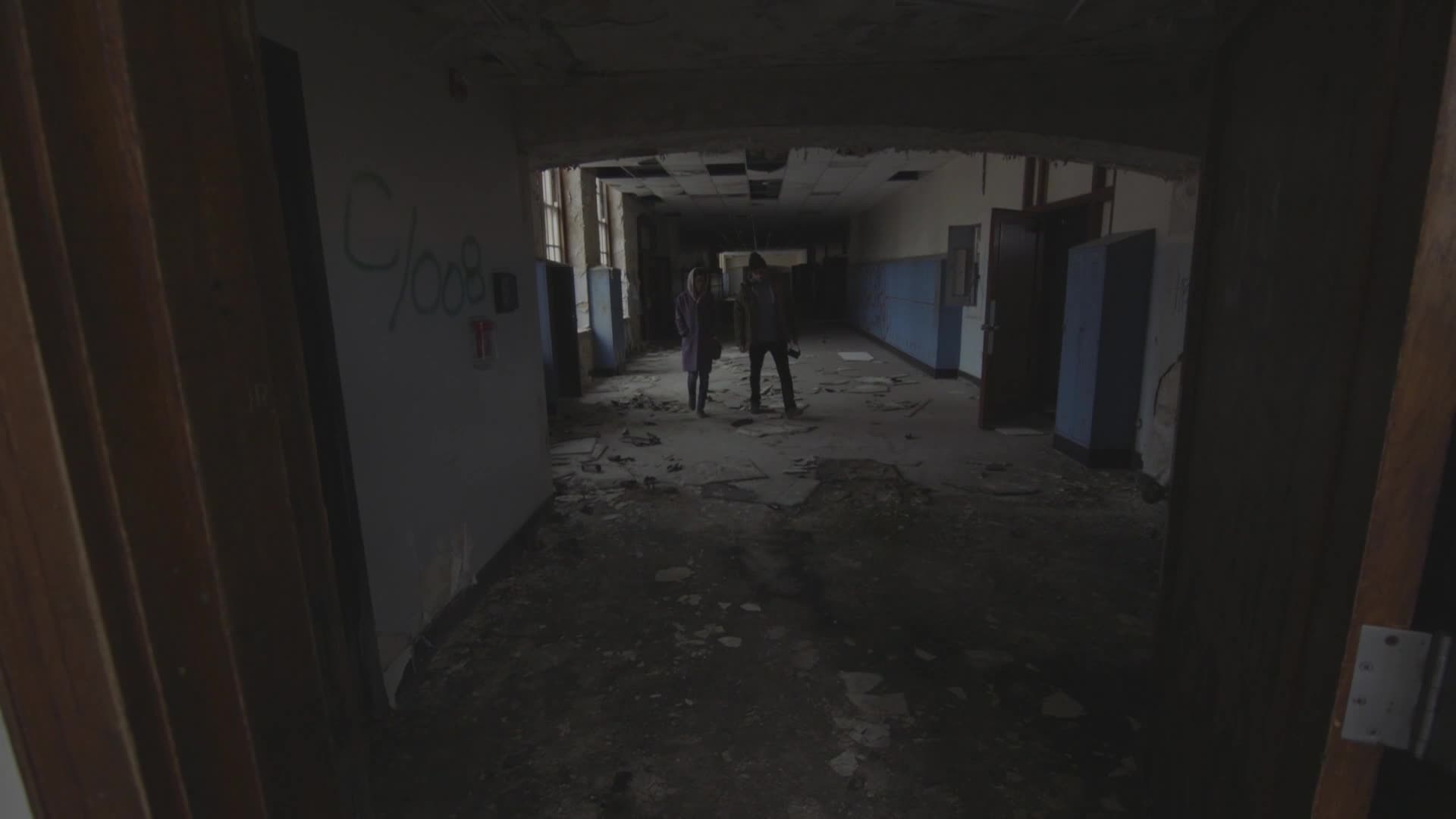 Two figures stand in a dilapidated hallway, the floor littered with debris. The scene, shot for VICE TV in the United States, feels eerie and abandoned.
