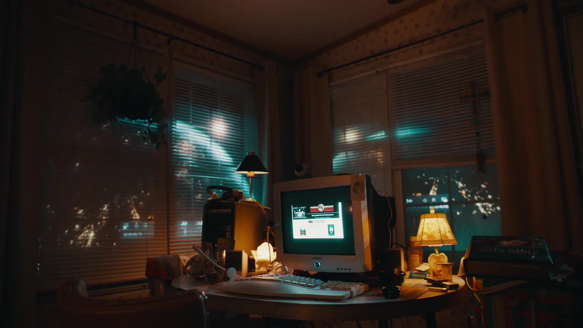 The old CRT monitor glows with a stark white interface, casting a cool light across the cluttered desk. Outside the blinds, city lights shimmer through the darkness, a common sight in any American town.