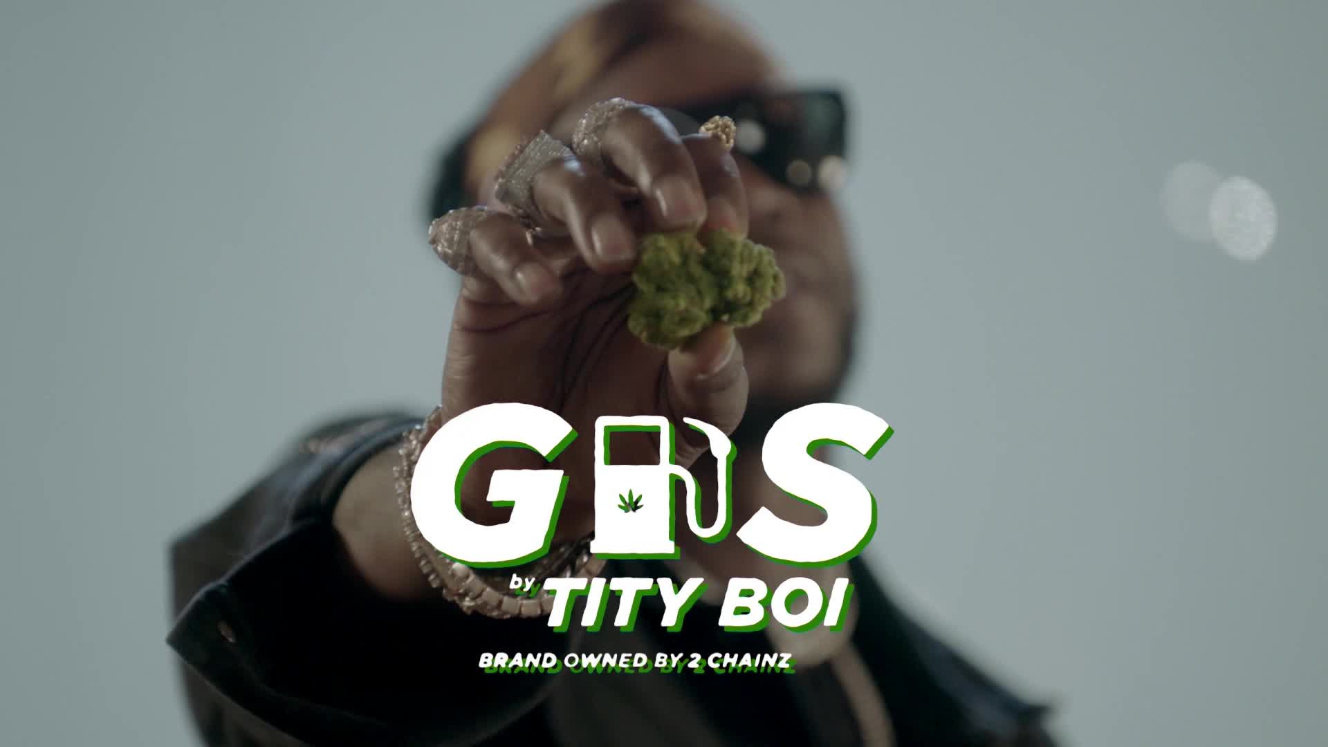 A hand holds up a bud of cannabis, glistening under the lights. Bold white letters spell out "GAS," with a gas pump icon replacing the "A."