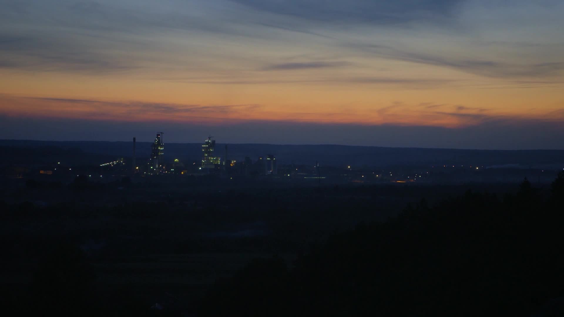 The sky bleeds orange and purple over a distant industrial complex, its towers lit against the fading light. This is the kind of landscape VICE TV often explores, a stark reminder of American industry working through the night.