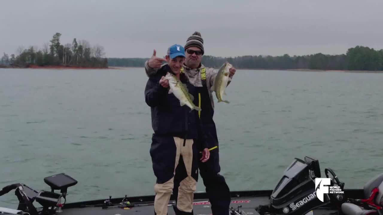 Two anglers on a boat pose with their catches, holding up the fish for the camera. The World Fishing Network logo is visible as they show off their success on the water.
