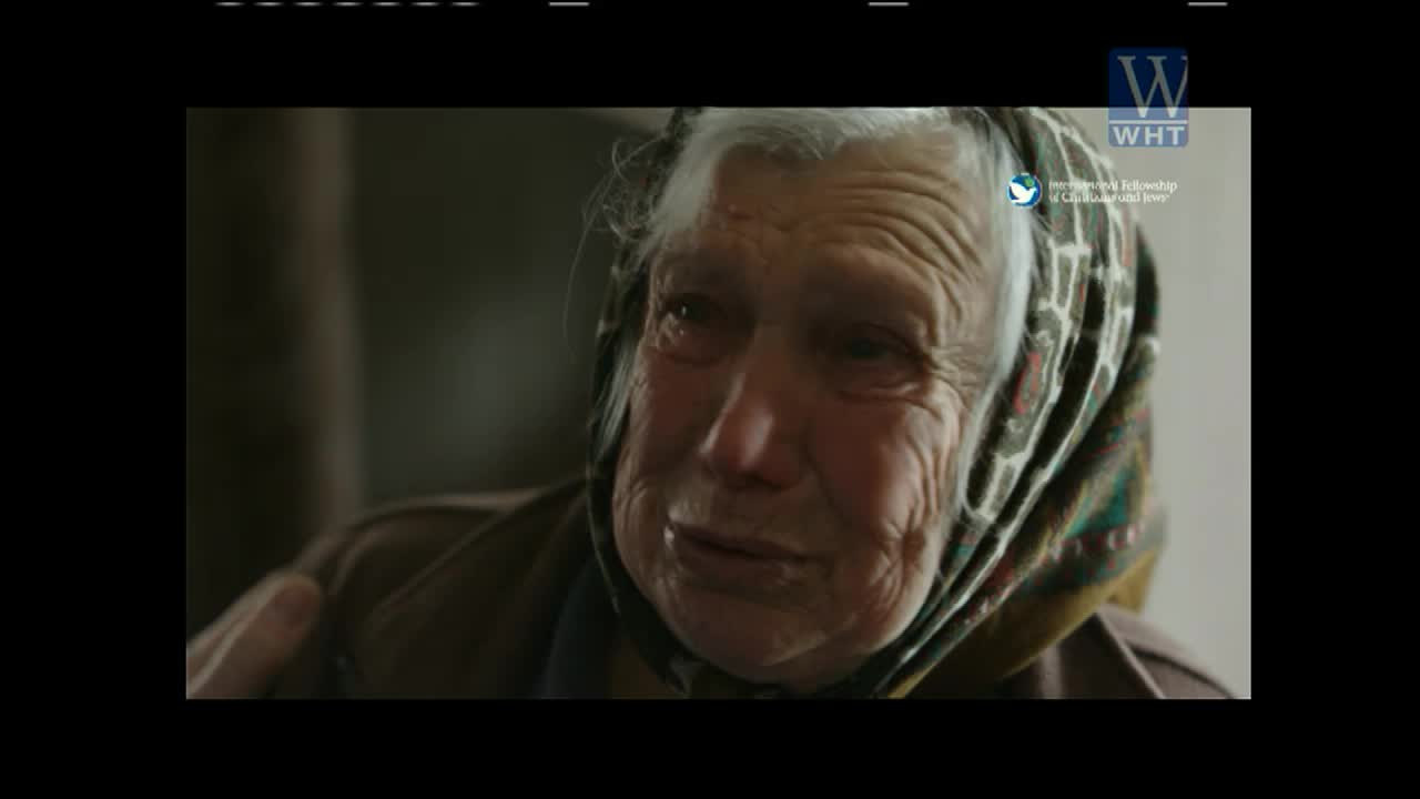 An elderly woman, her face etched with lines, is speaking, tears welling in her eyes. The World Harvest TV logo sits in the corner, seemingly documenting her story.

