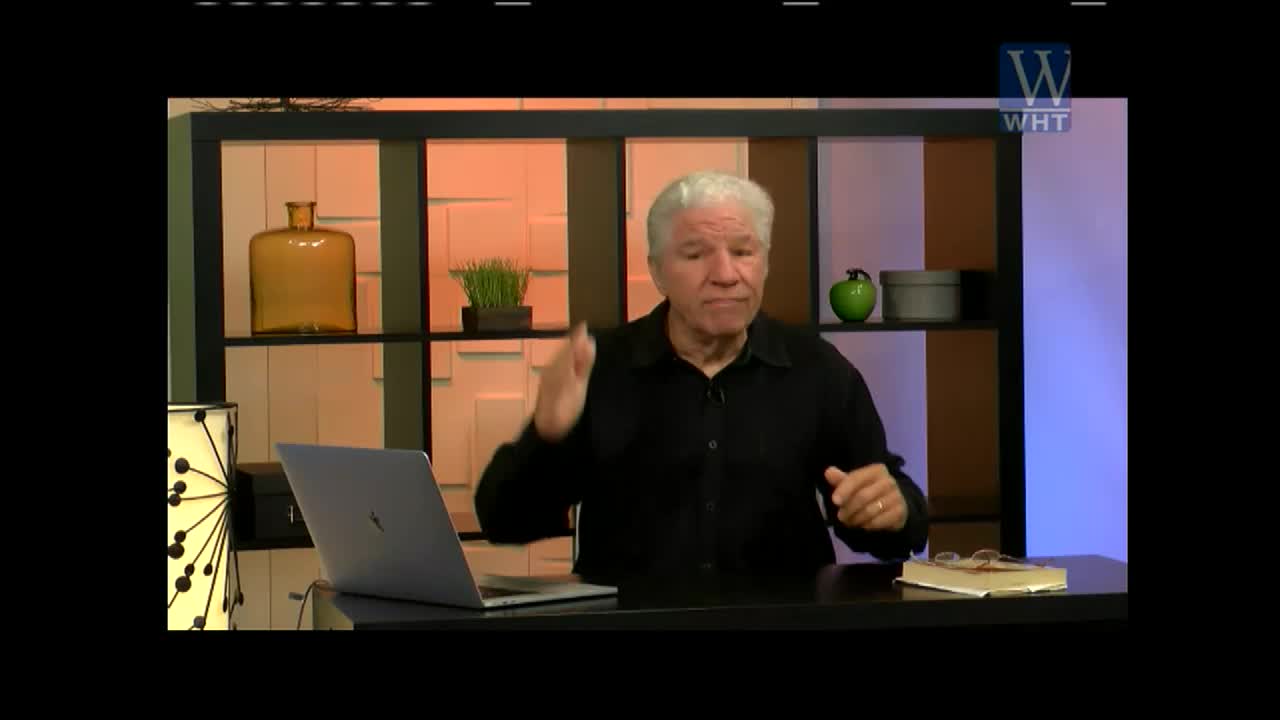 A man with white hair gestures with his right hand, speaking from behind a desk. He's in a studio, with the World Harvest TV logo visible in the corner.
