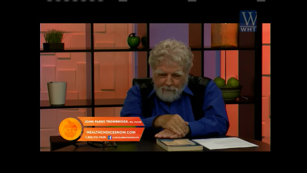 A man with a white beard sits at a desk, looking down at a book. The set, likely for World Harvest TV, has a warm, orange glow.
