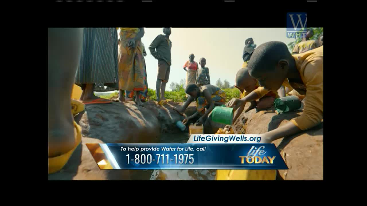Children are gathered around a well, filling containers with water. A banner from "Life Today" on World Harvest TV encourages viewers in the United States to donate to "Life Giving Wells."
